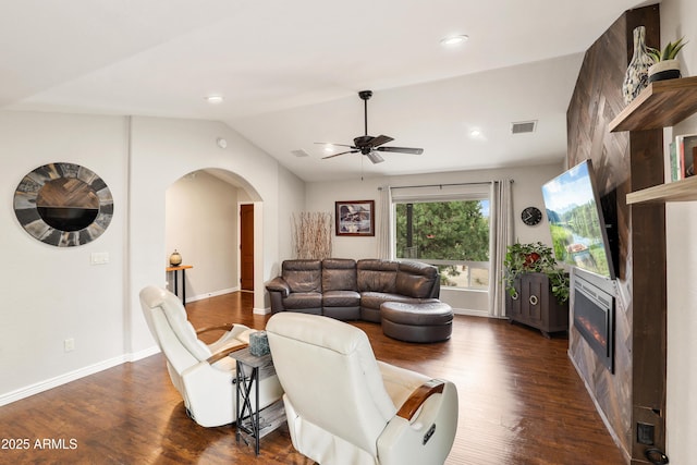 living area with arched walkways, dark wood finished floors, lofted ceiling, visible vents, and a glass covered fireplace