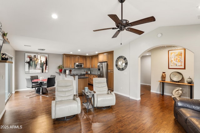 living area featuring arched walkways, dark wood-style flooring, ceiling fan, and baseboards