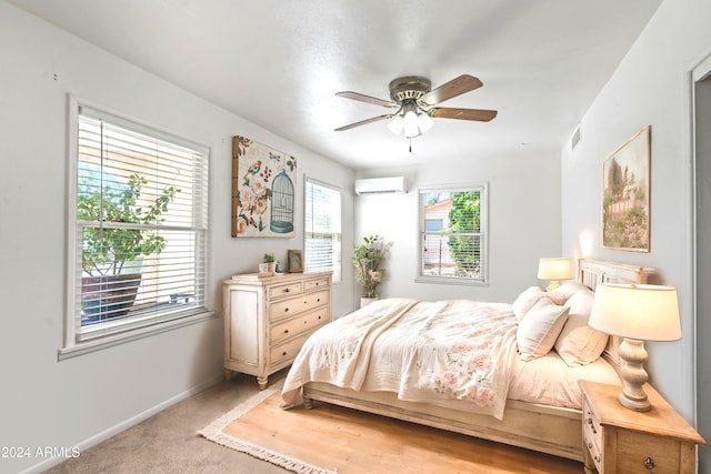 bedroom featuring a wall unit AC, visible vents, light carpet, ceiling fan, and baseboards