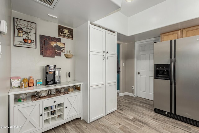 3061 W Betty Elyse Ln, Phoenix, AZ 85053 - kitchen featuring stainless steel fridge with ice dispenser, light wood-type flooring, white cabinets, and light countertops