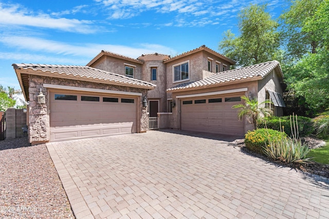 mediterranean / spanish-style house with an attached garage, decorative driveway, stucco siding, and a tile roof