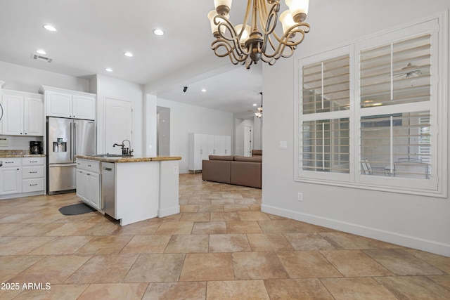 kitchen with a sink, stainless steel appliances, open floor plan, baseboards, and visible vents