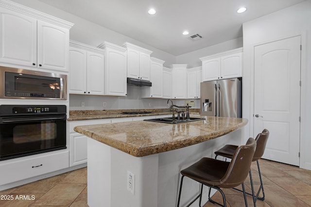 kitchen with a sink, black appliances, a kitchen bar, and white cabinetry