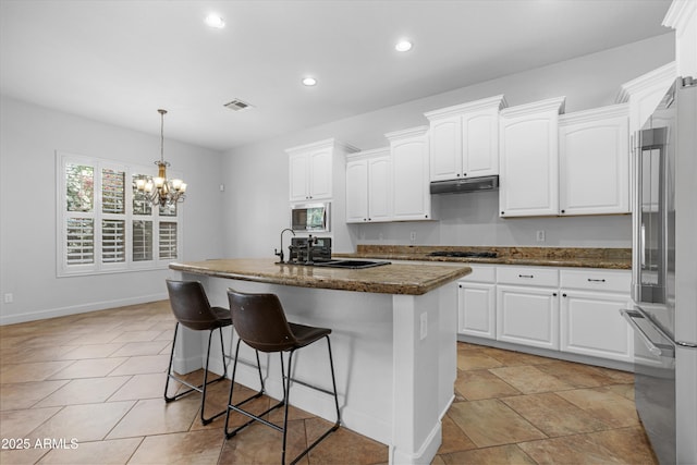 kitchen with recessed lighting, white cabinetry, under cabinet range hood, a sink, and appliances with stainless steel finishes