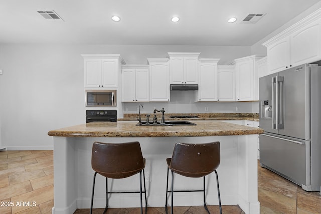 kitchen with a sink, appliances with stainless steel finishes, under cabinet range hood, and white cabinets