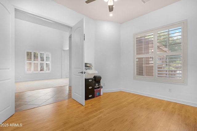 empty room with a healthy amount of sunlight, a ceiling fan, and wood finished floors