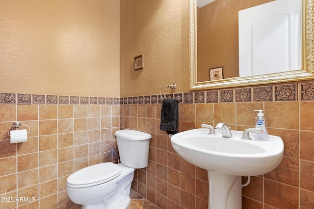 bathroom with toilet and tile walls