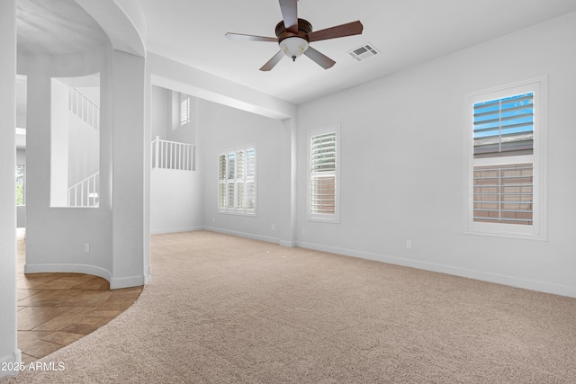 carpeted empty room featuring baseboards, ceiling fan, and visible vents