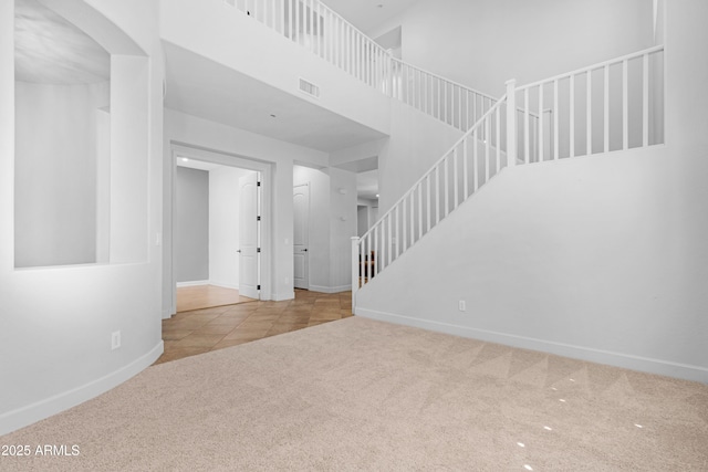 unfurnished living room with visible vents, baseboards, tile patterned floors, arched walkways, and carpet