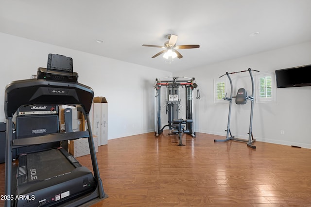 workout room featuring baseboards, ceiling fan, and wood finished floors