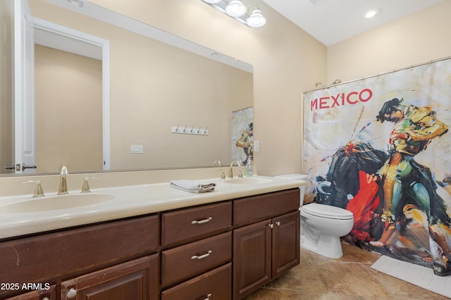 bathroom featuring double vanity, a sink, and toilet