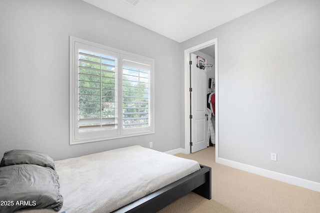 bedroom featuring baseboards, a spacious closet, and light carpet