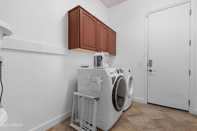 clothes washing area featuring baseboards, washer and clothes dryer, cabinet space, and stone finish flooring