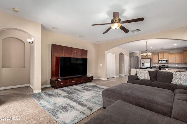 living area with visible vents, baseboards, light carpet, arched walkways, and ceiling fan with notable chandelier