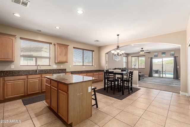 kitchen featuring a healthy amount of sunlight, light tile patterned floors, a breakfast bar, a kitchen island, and visible vents