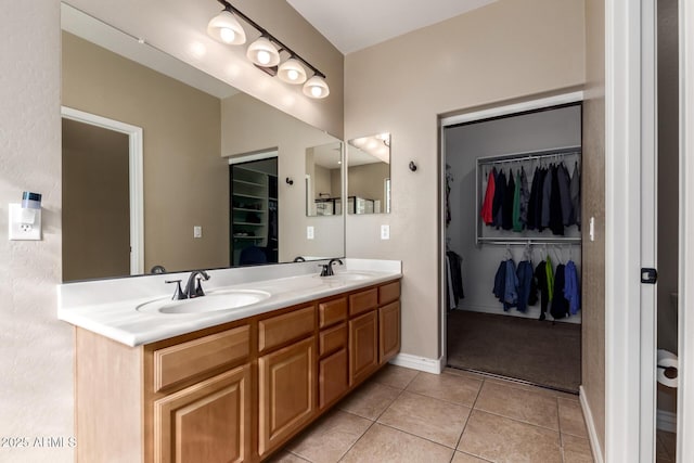 full bath featuring double vanity, a sink, tile patterned floors, and a spacious closet