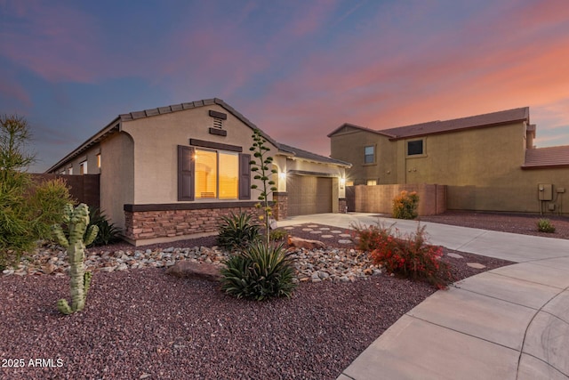 view of front facade with a garage, driveway, stucco siding, and fence