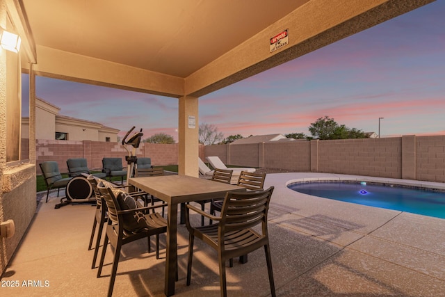 patio terrace at dusk with a fenced backyard, outdoor dining space, and a fenced in pool