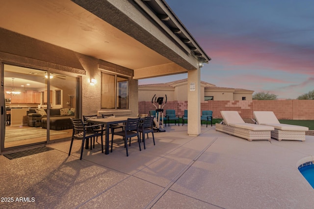 patio terrace at dusk with outdoor dining area and fence
