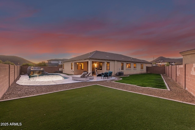 back of property at dusk with central air condition unit, a lawn, a fenced backyard, and a patio area