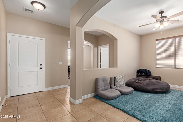 entrance foyer with visible vents, baseboards, a ceiling fan, arched walkways, and light tile patterned floors