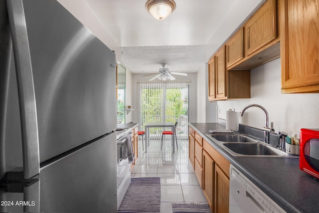 kitchen featuring light tile patterned floors, white dishwasher, ceiling fan, stainless steel fridge, and sink