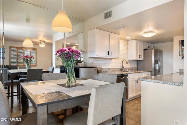 kitchen featuring white cabinetry, ceiling fan, hanging light fixtures, stainless steel fridge with ice dispenser, and light stone counters