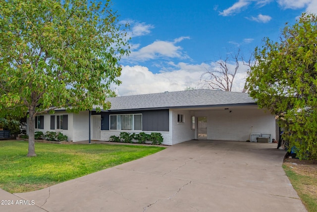 ranch-style home featuring a front yard, a carport, roof with shingles, and driveway