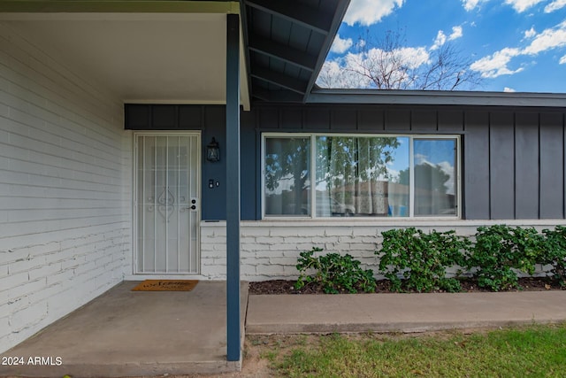 property entrance with board and batten siding and brick siding