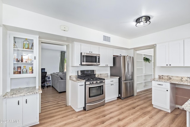 kitchen featuring white cabinetry, stainless steel appliances, light wood finished floors, and visible vents