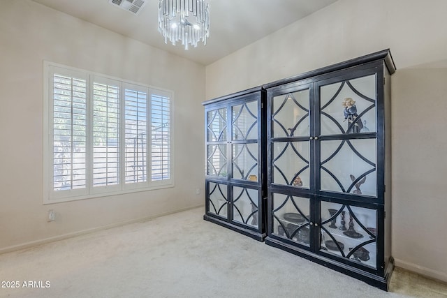 carpeted spare room featuring an inviting chandelier