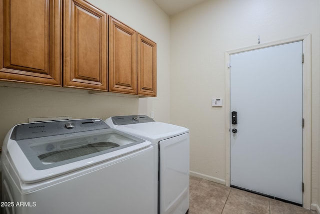 laundry area featuring washing machine and dryer, light tile patterned floors, and cabinets