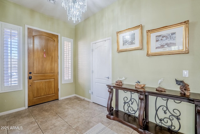 tiled entrance foyer with a healthy amount of sunlight and an inviting chandelier