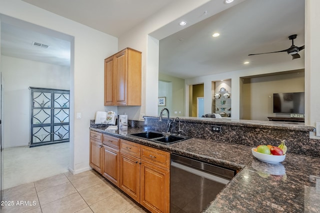 kitchen featuring ceiling fan, sink, stainless steel dishwasher, dark stone counters, and light carpet