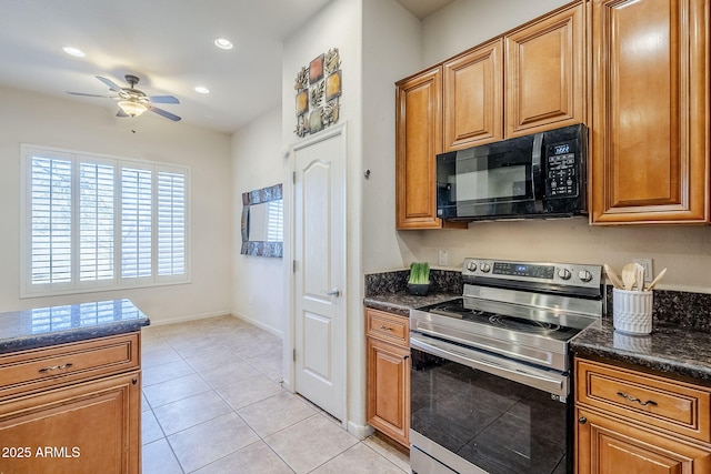 kitchen with ceiling fan, light tile patterned floors, stainless steel range with electric stovetop, and dark stone countertops