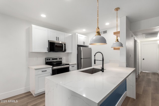 5230 E Brown Rd Unit 114, Mesa, AZ 85205 - kitchen with appliances with stainless steel finishes, light wood finished floors, white cabinets, a peninsula, and light stone countertops