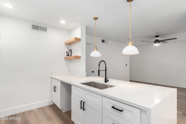 5230 E Brown Rd Unit 114, Mesa, AZ 85205 - kitchen with light wood-style flooring, open shelves, white cabinetry, pendant lighting, and light stone counters