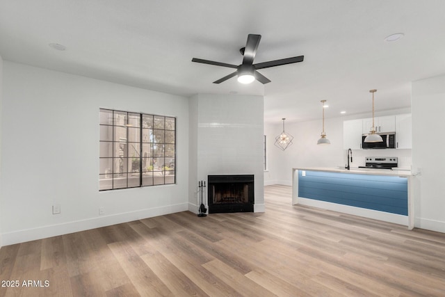 5230 E Brown Rd Unit 114, Mesa, AZ 85205 - unfurnished living room with light wood-style flooring, a ceiling fan, a fireplace, and recessed lighting