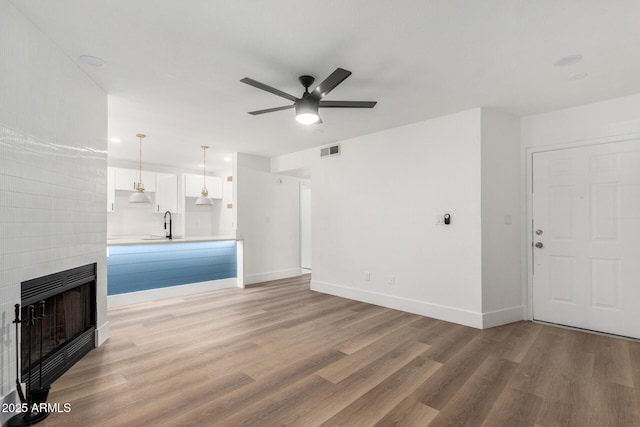 5230 E Brown Rd Unit 114, Mesa, AZ 85205 - unfurnished living room featuring light wood finished floors, a ceiling fan, a fireplace, and heating unit