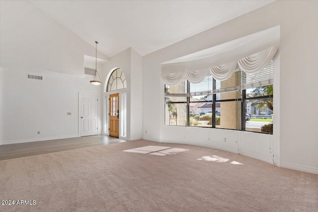 unfurnished living room featuring carpet and high vaulted ceiling