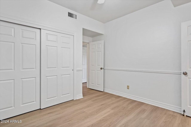 unfurnished bedroom with ceiling fan, a closet, and light wood-type flooring