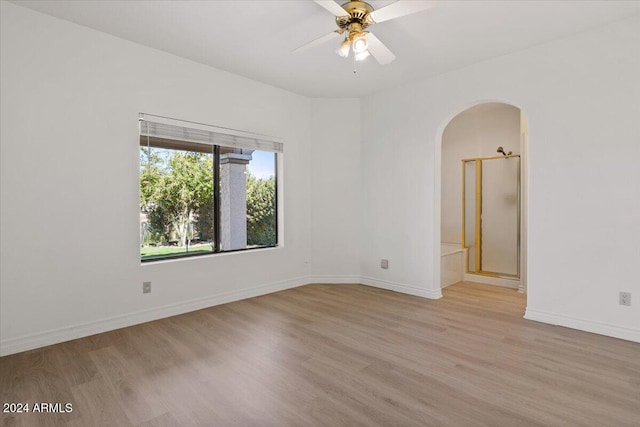 empty room with ceiling fan and light hardwood / wood-style flooring