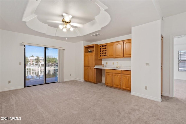 kitchen featuring light carpet, a tray ceiling, ceiling fan, and sink