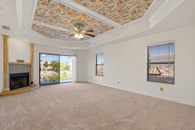 unfurnished living room with carpet, ceiling fan, ornamental molding, and a tray ceiling