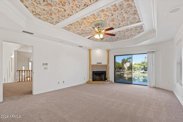 unfurnished living room with ceiling fan, a raised ceiling, light carpet, a fireplace, and ornamental molding