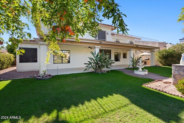 rear view of house featuring a lawn, ceiling fan, a balcony, and a patio