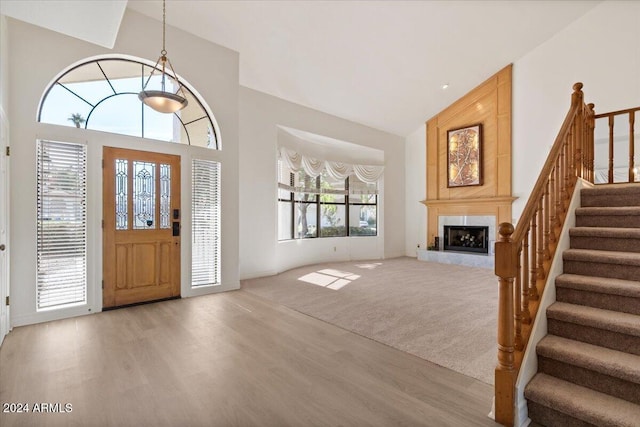 foyer entrance with a large fireplace, light hardwood / wood-style floors, and high vaulted ceiling