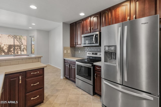 kitchen with appliances with stainless steel finishes, light stone countertops, and backsplash