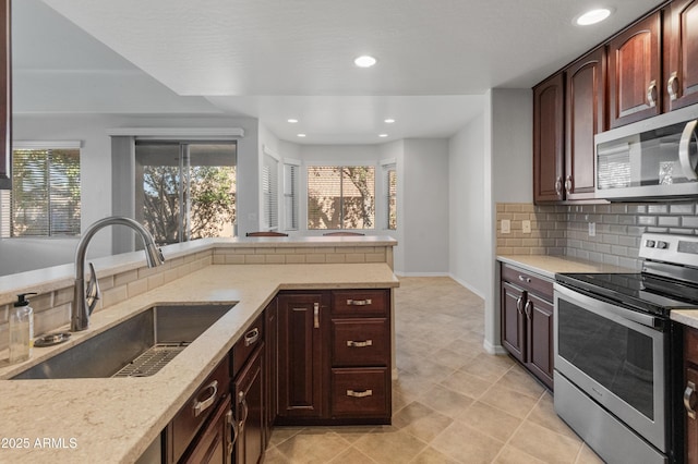 kitchen with sink, decorative backsplash, light stone counters, stainless steel appliances, and plenty of natural light