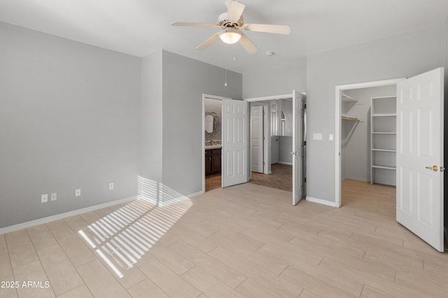 unfurnished bedroom with ensuite bathroom, a walk in closet, light wood-type flooring, a closet, and ceiling fan